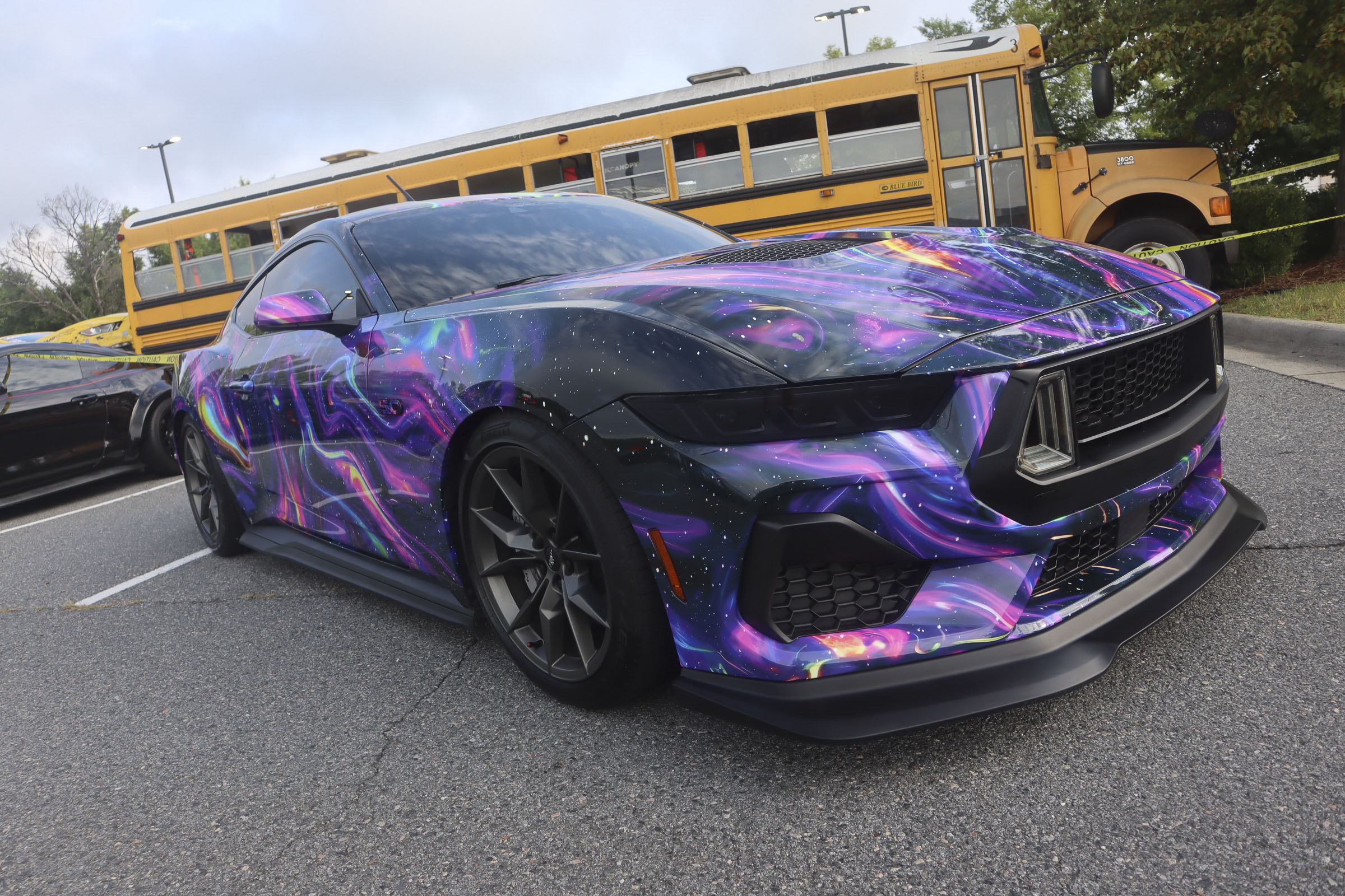 Purple galaxy wrap Mustang sports car at Mustang Week event.