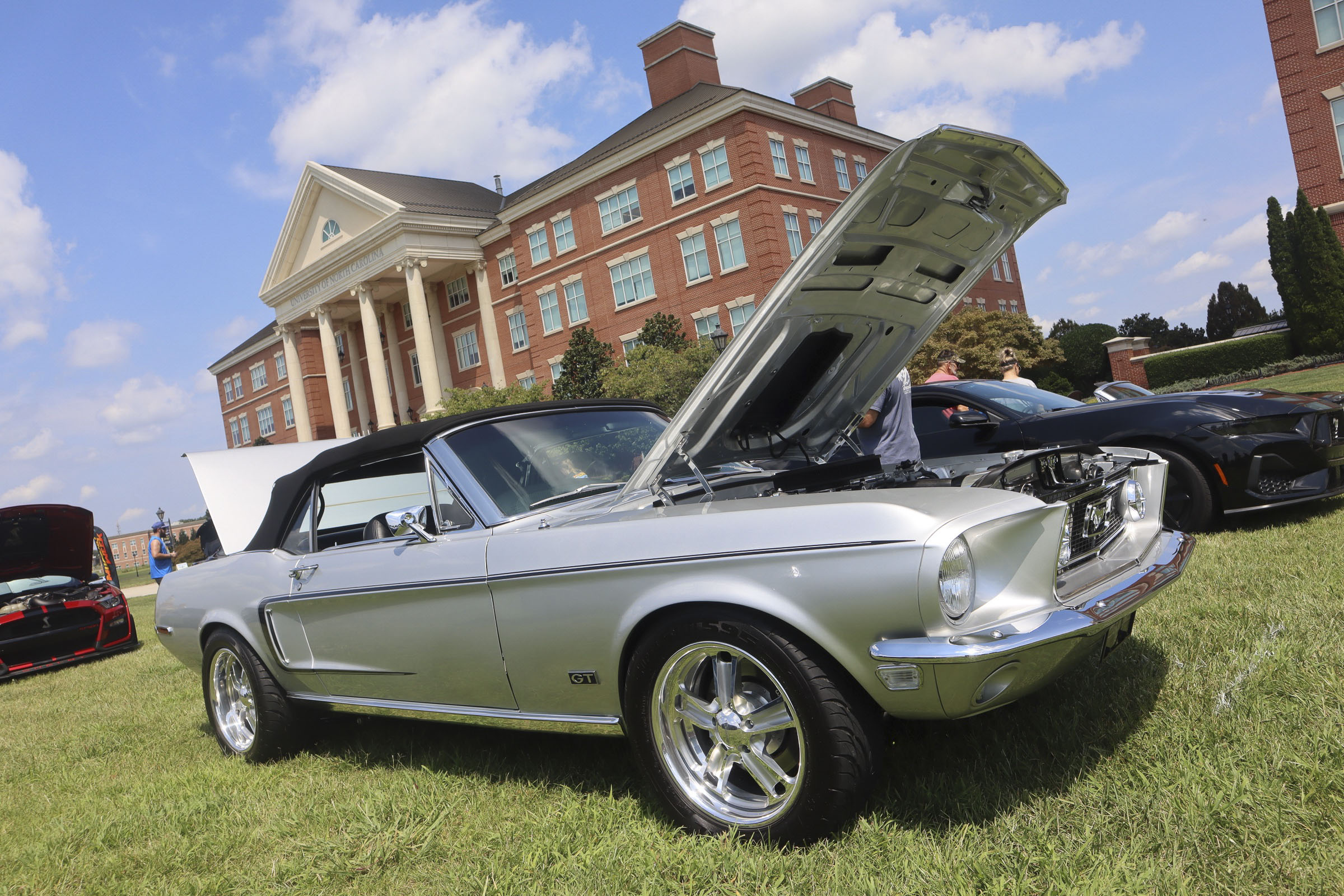Silver Ford Mustang convertible with open hood at Mustang Week event.