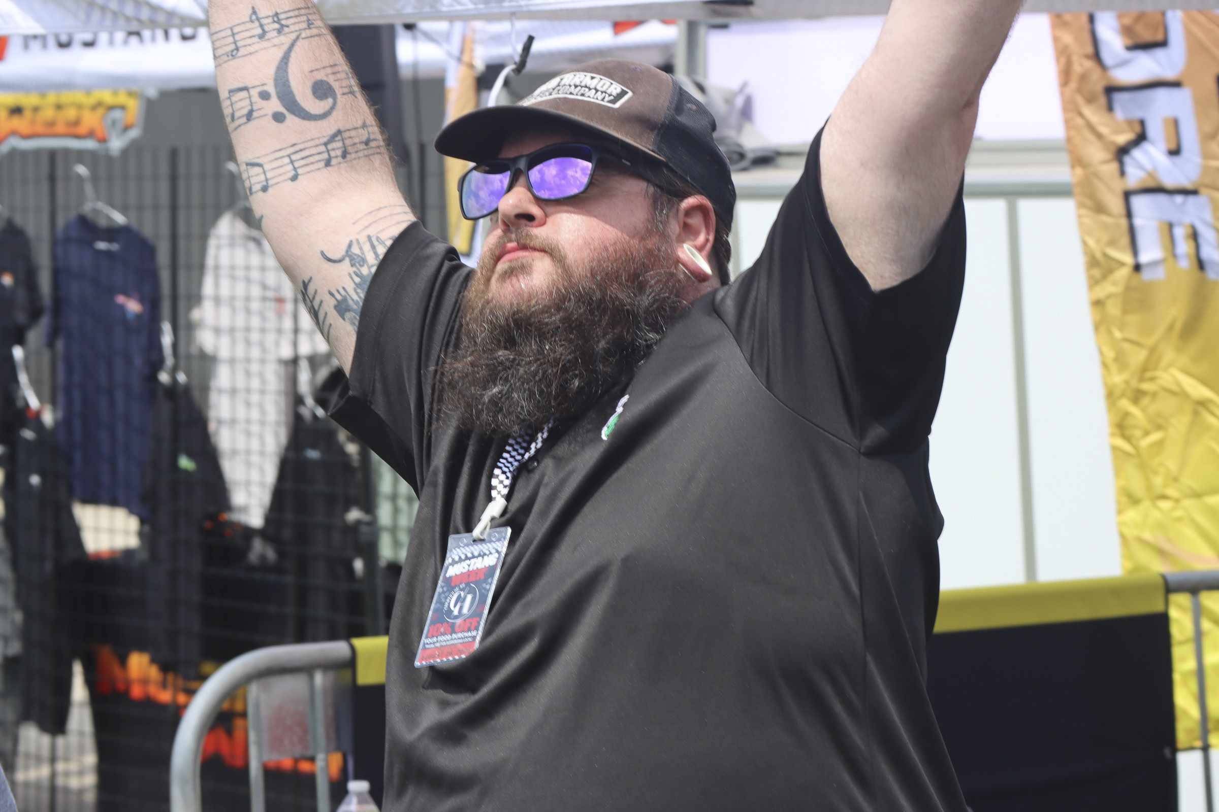 Man with beard and sunglasses celebrating at Mustang Week event.