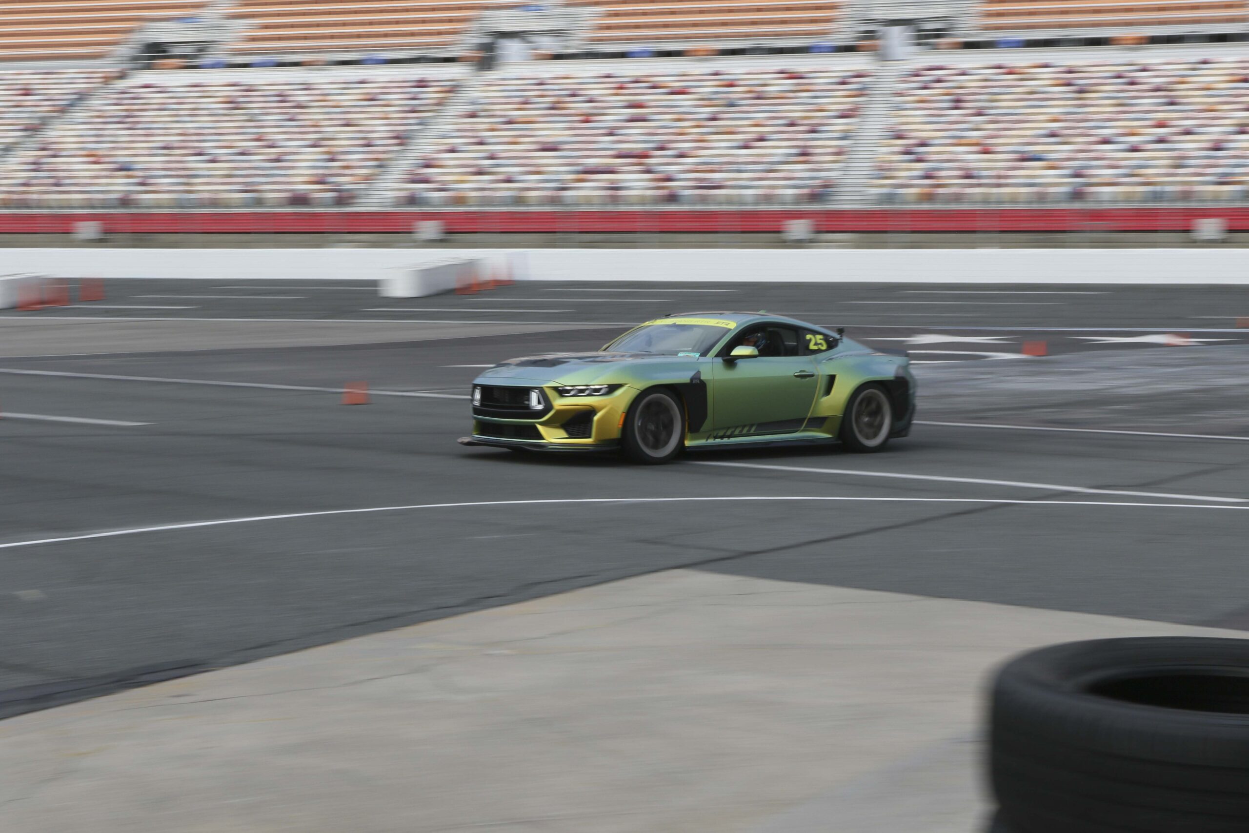 Green and black Mustang race car on the track at Mustang Week event.