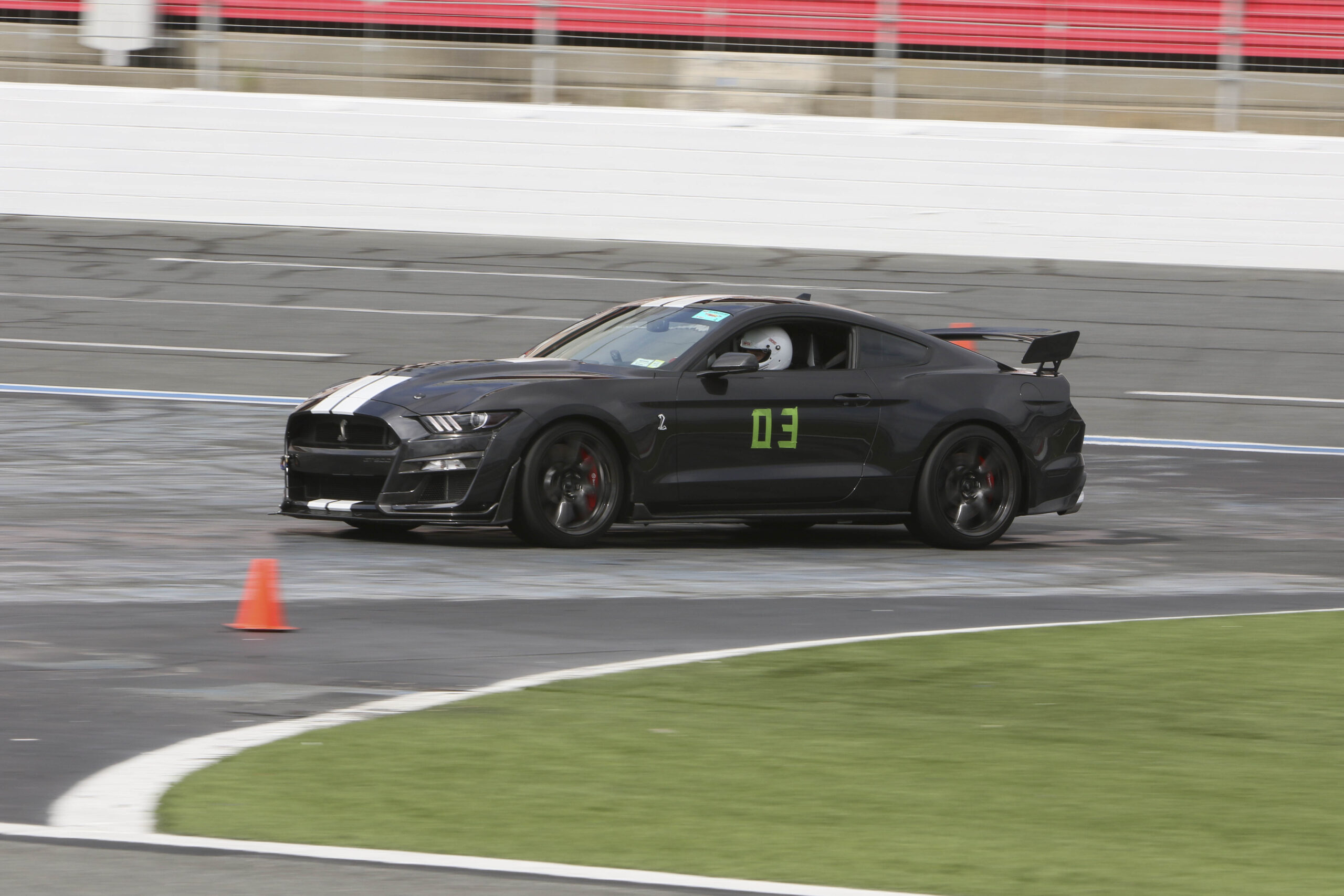 Black Ford Mustang race car on track at Mustang Week Charlotte 2026 event.