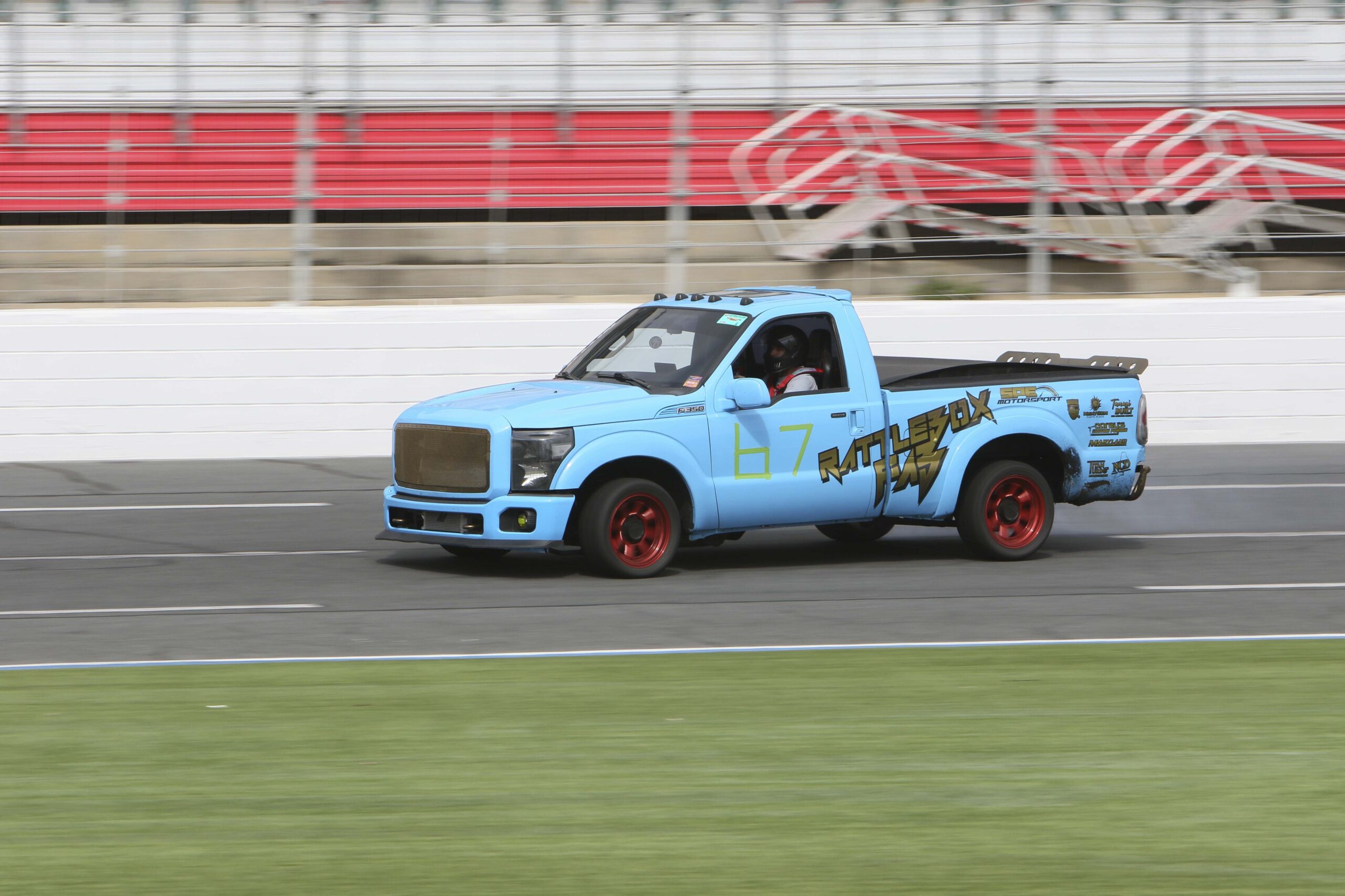 Blue race truck with red wheels on track at Mustang Week Charlotte 2026.