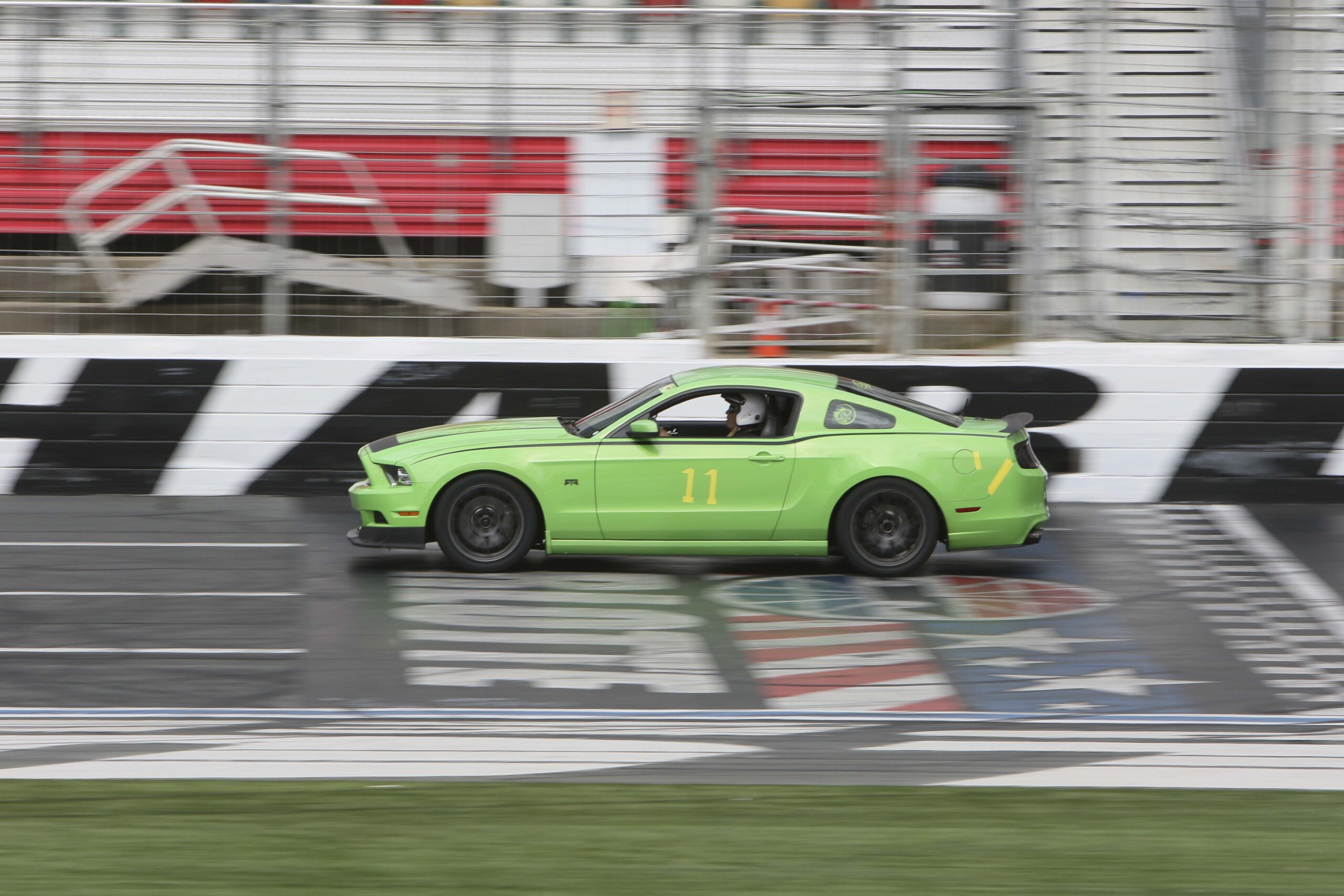 Green Mustang race car on track at Charlotte 2026 event.
