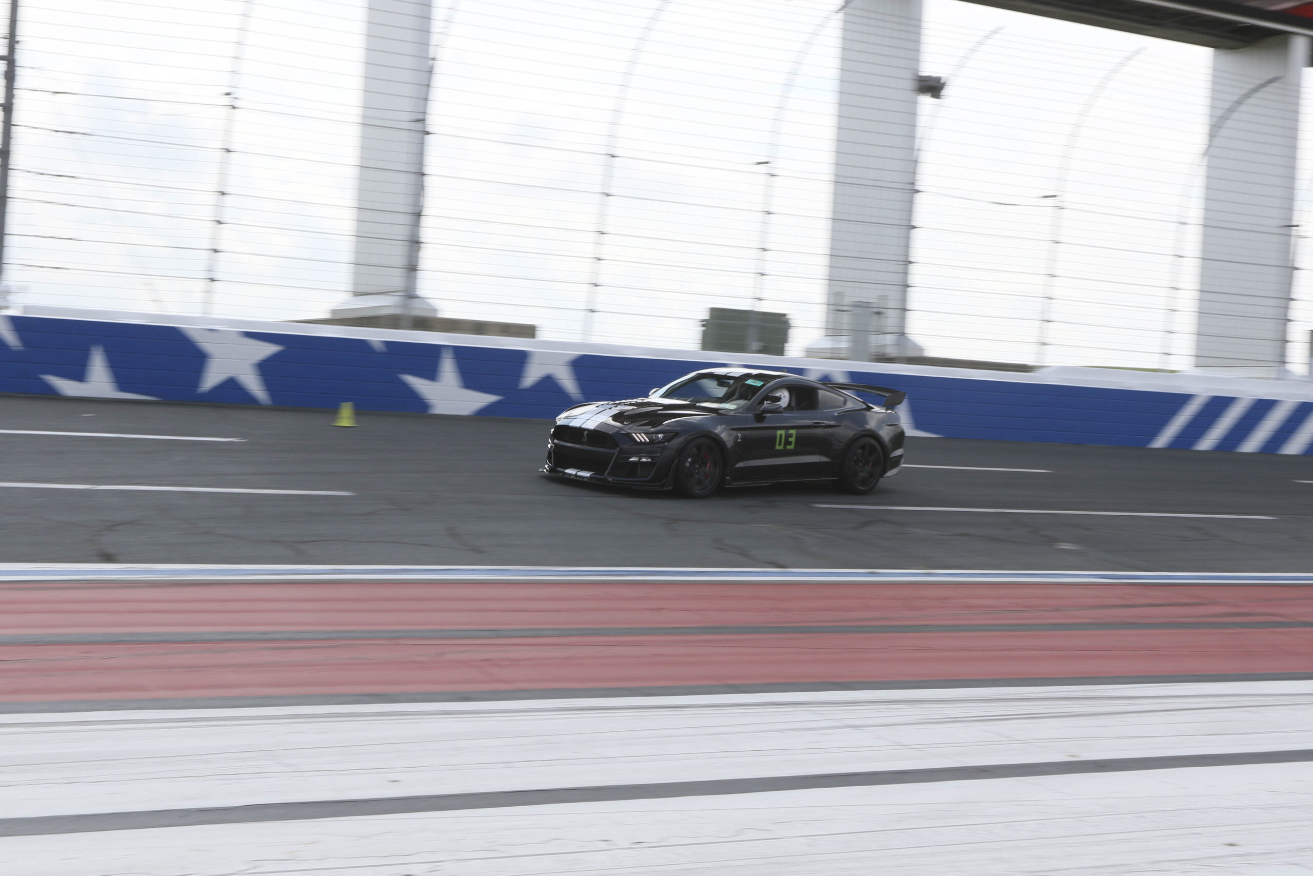 Black Mustang race car on indoor racing track at Mustang Week.