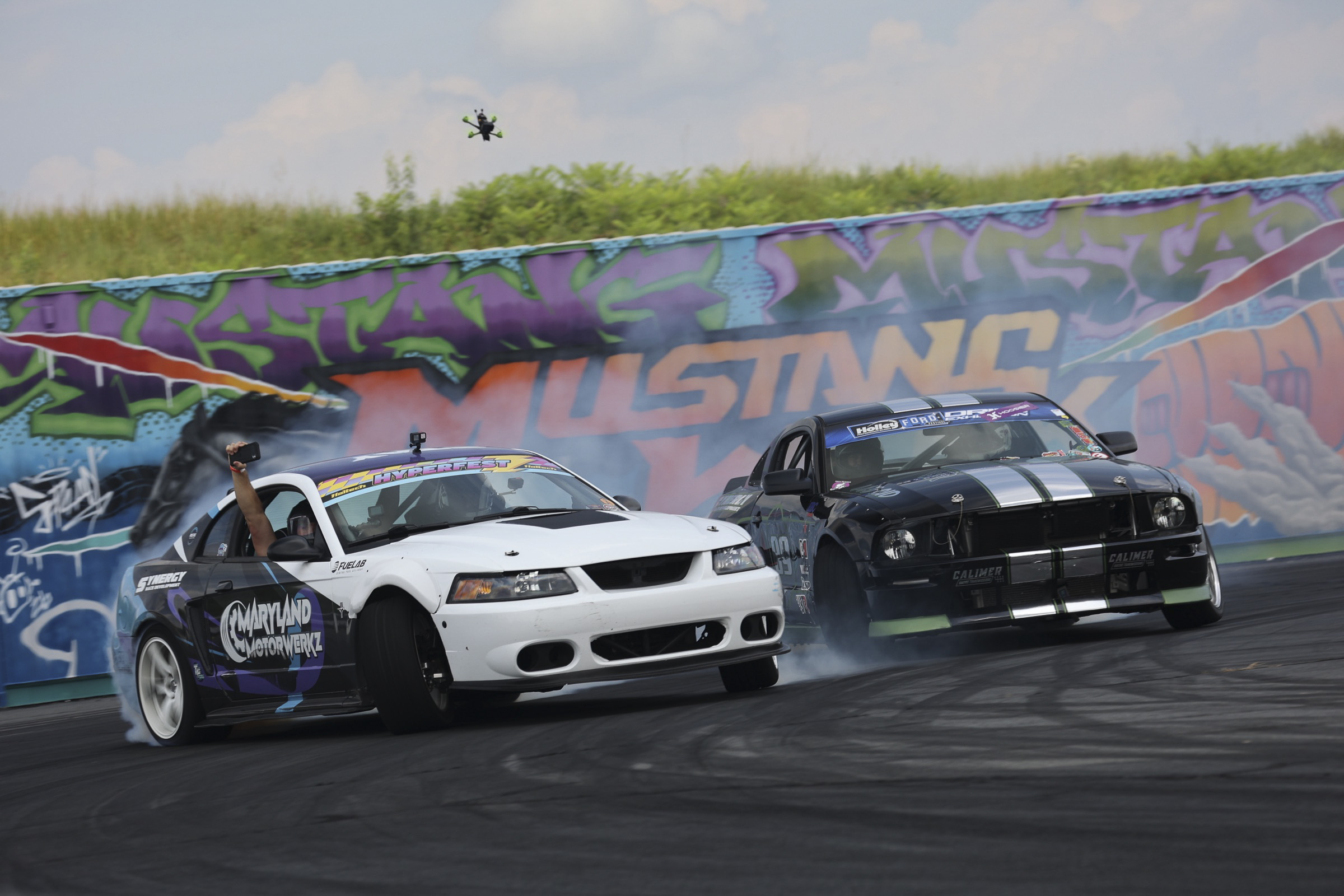Two Ford Mustangs drifting on a race track during Mustang Week event.