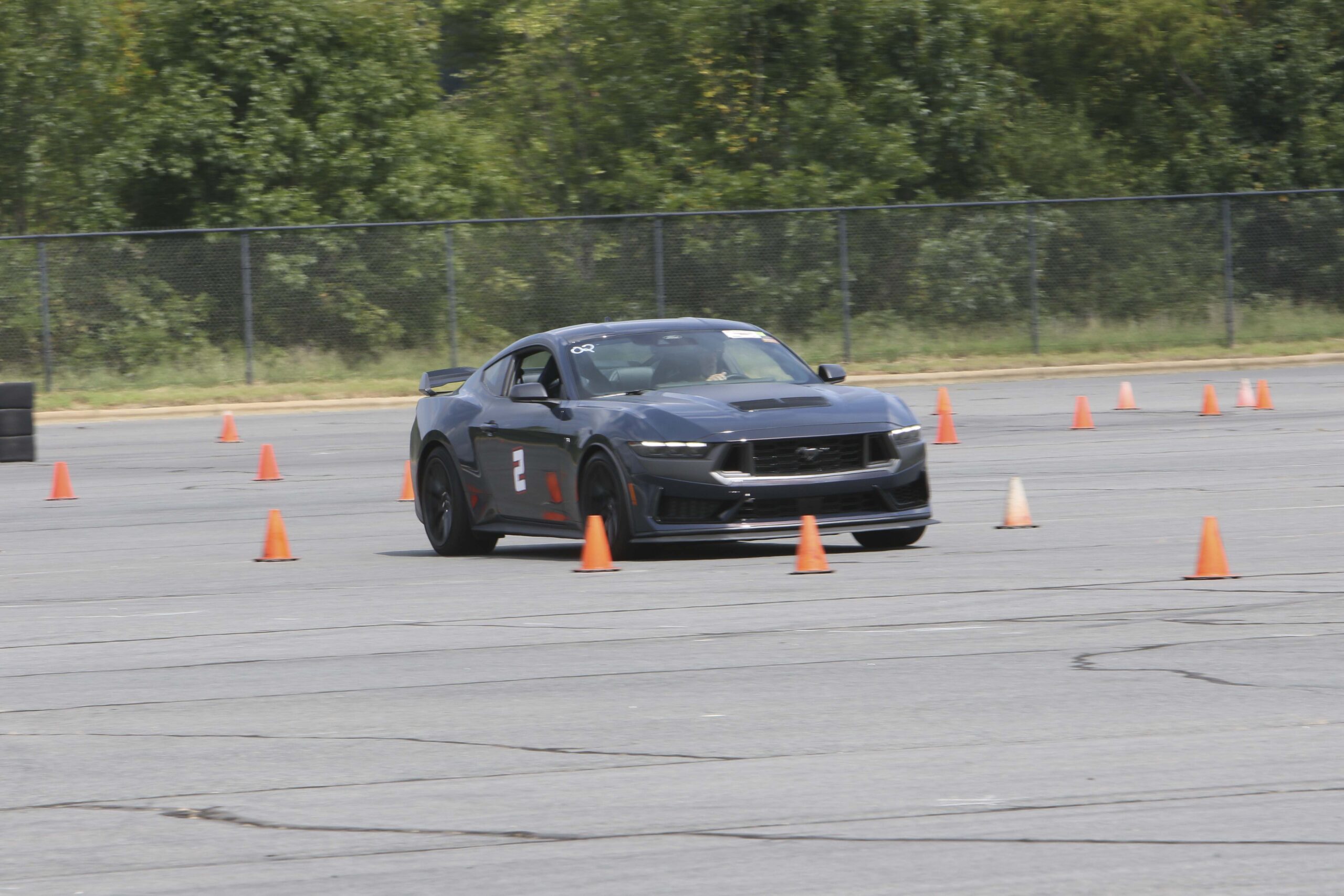 Black Ford Mustang drifting through cones at Mustang Week event.