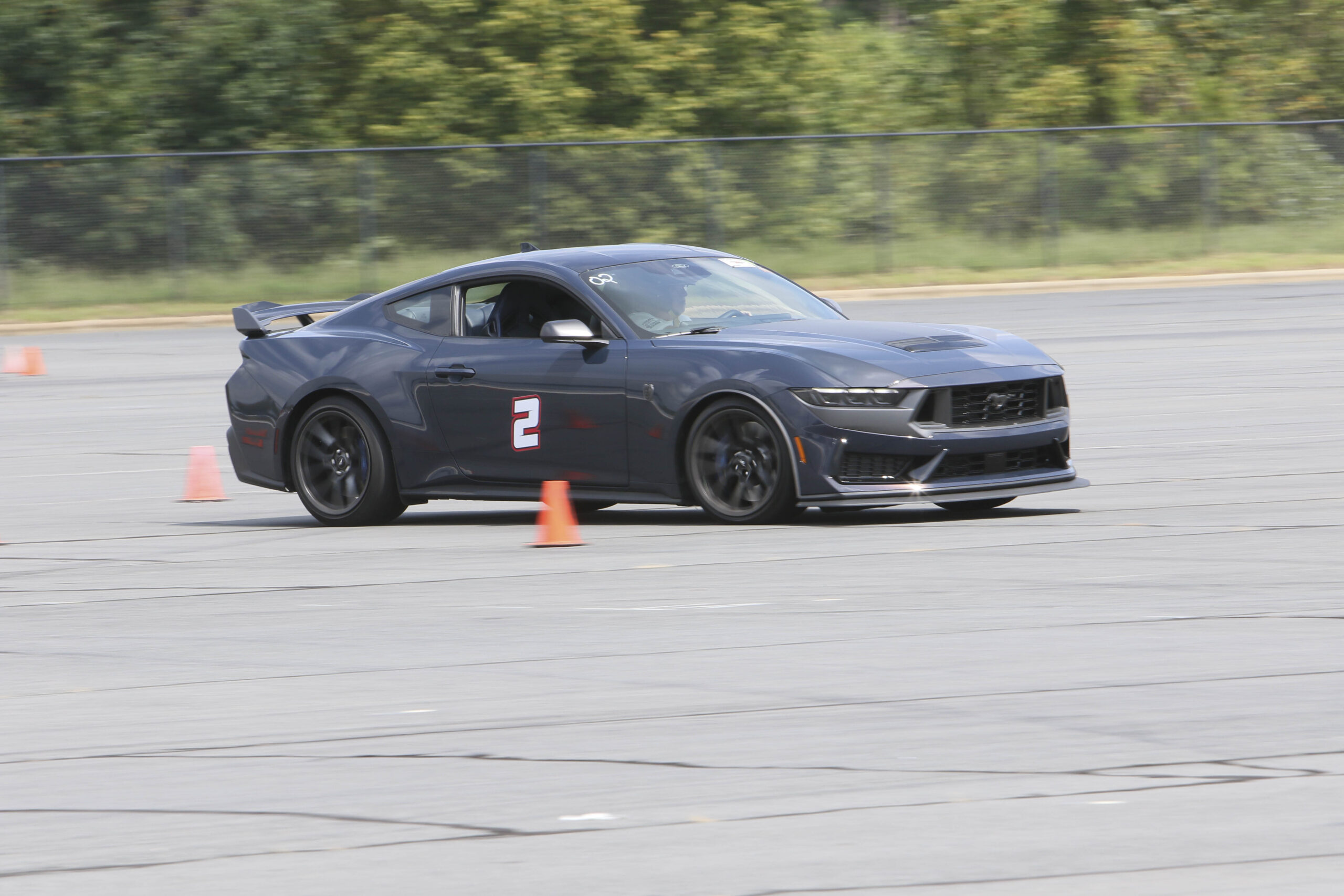 Black Ford Mustang racing through cones at Mustang Week event.