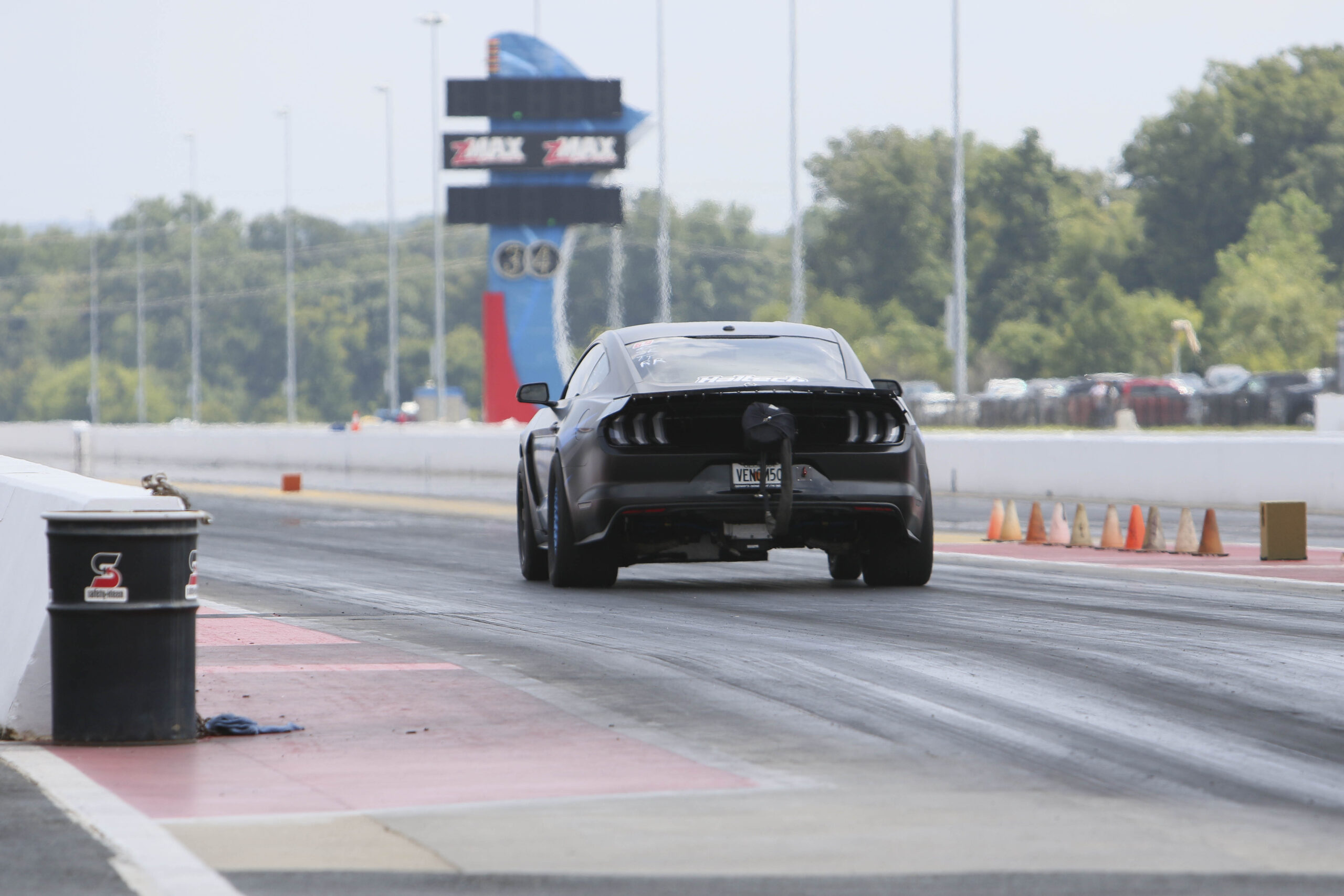 Black Ford Mustang drag racing on the track at Mustang Week event.