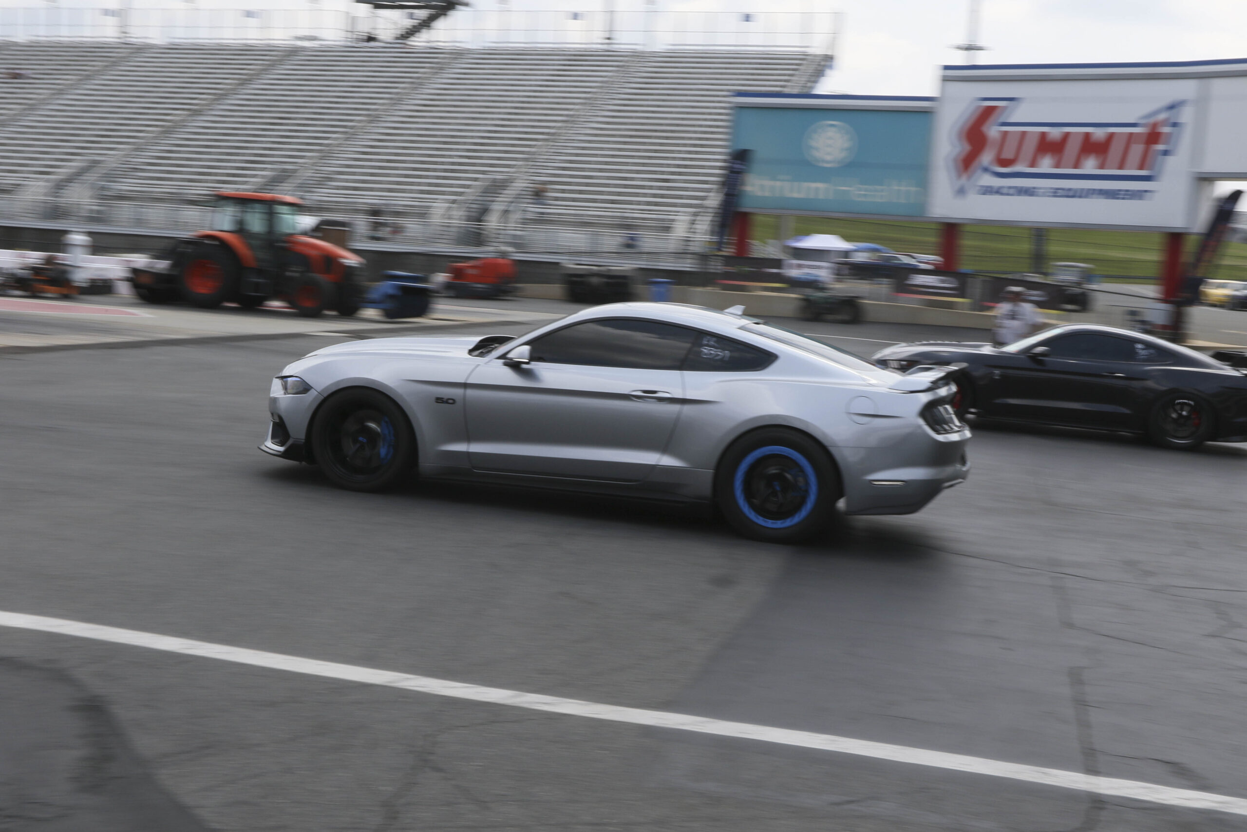 Silver Ford Mustang with custom blue wheels at Charlotte 2026 event.