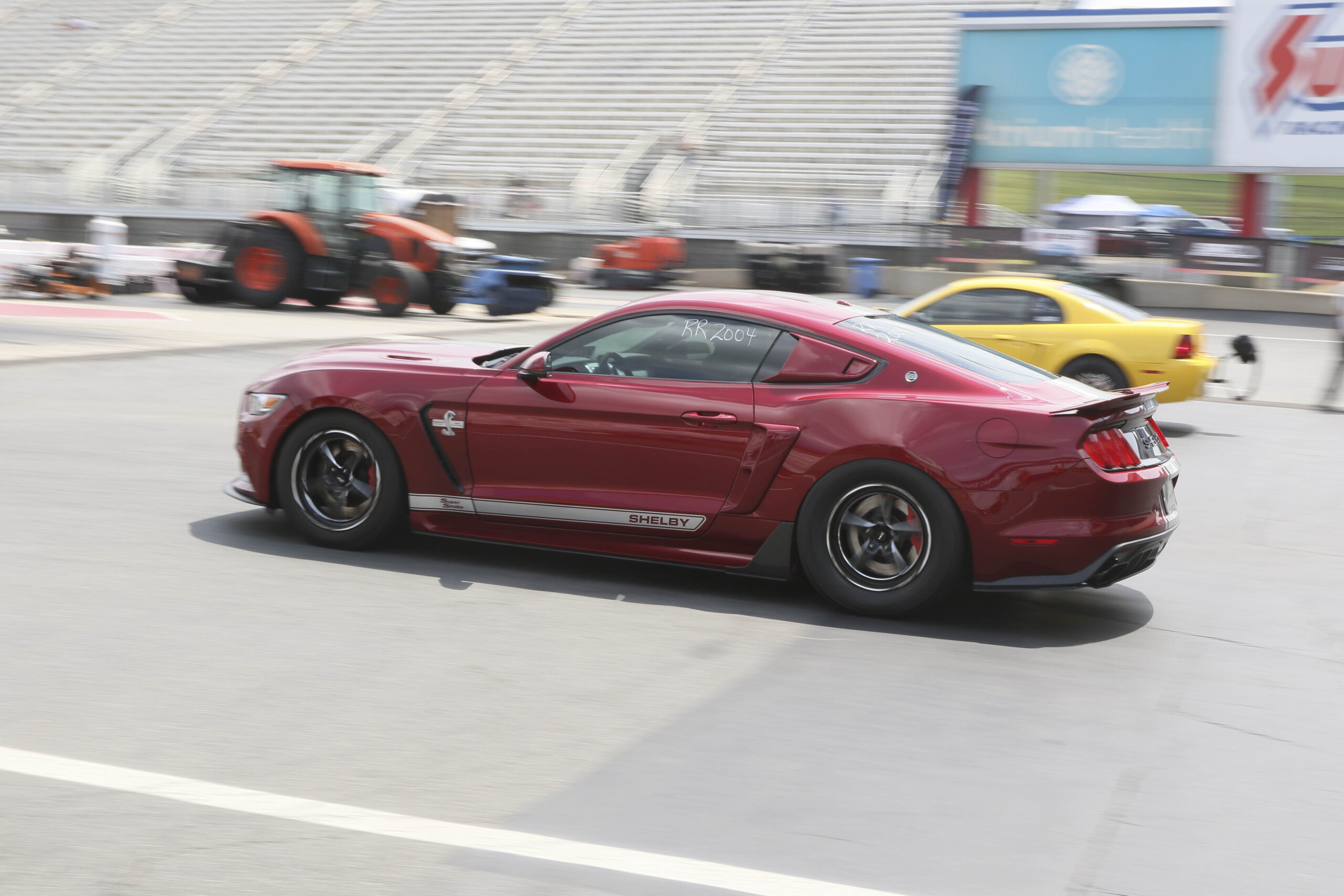 Red Ford Mustang GT racing at Charlotte Motor Speedway.