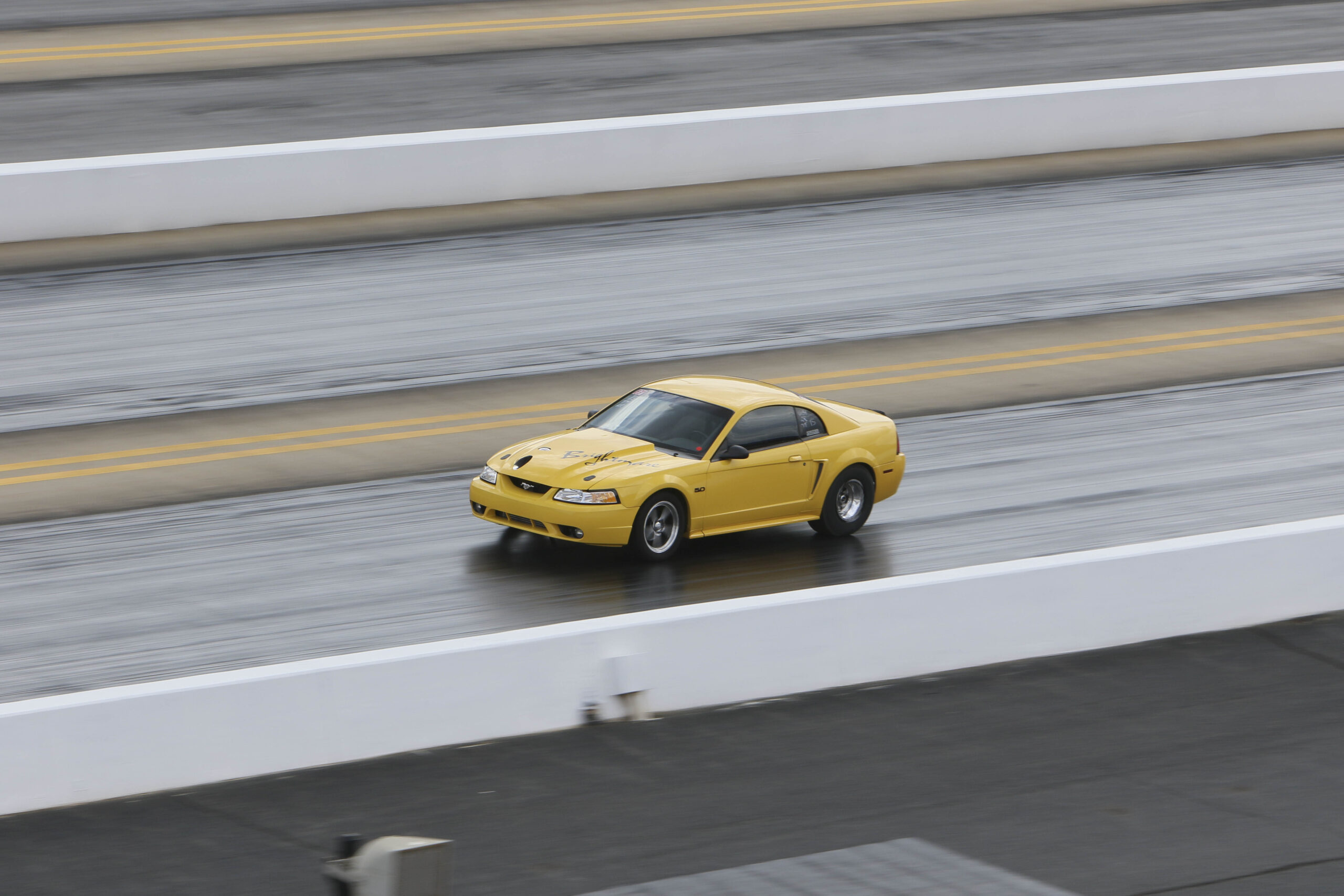 Yellow Chevrolet Camaro racing on a drag strip during Mustang Week.