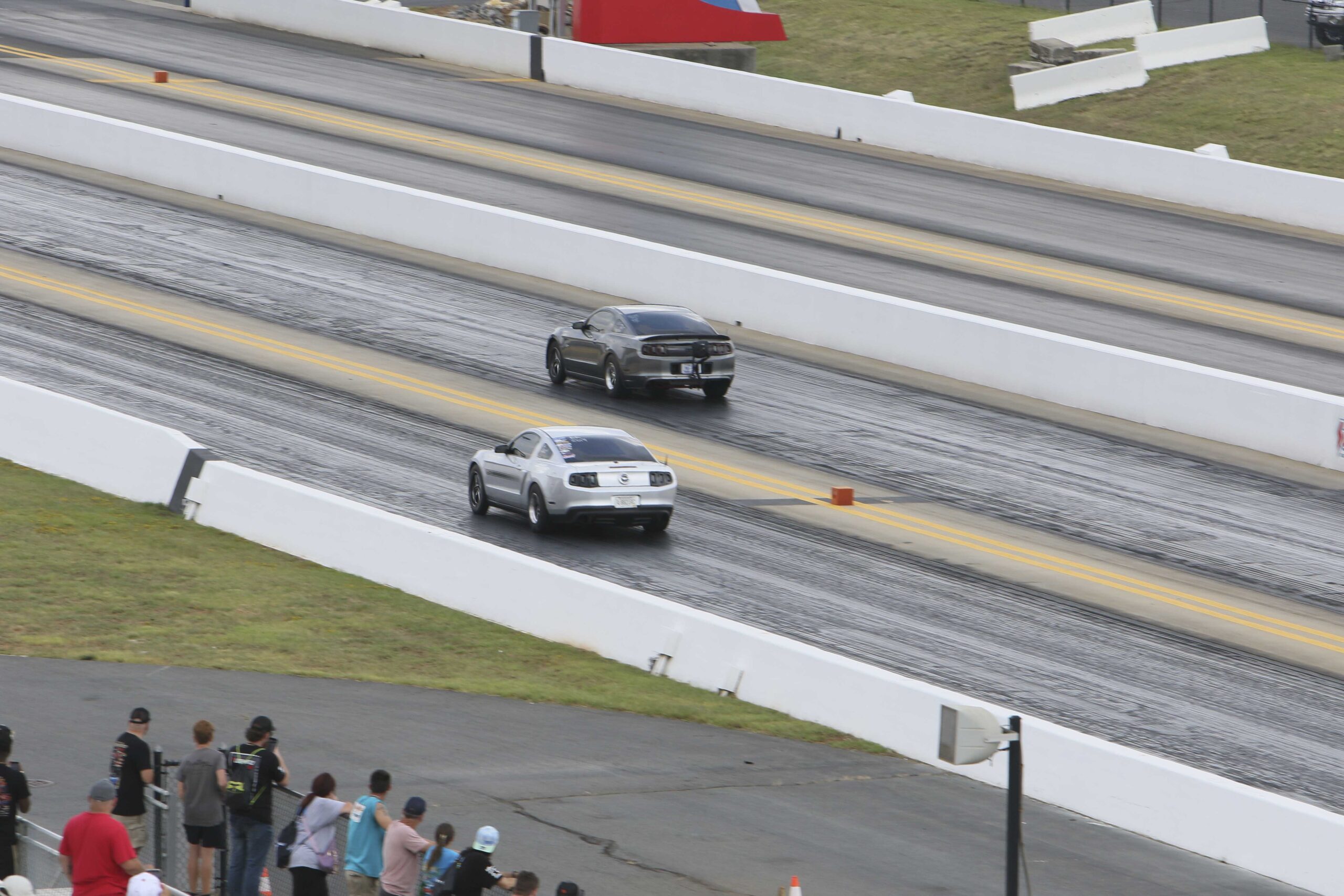 Mustang Week drag racing with two cars on the track and spectators watching.
