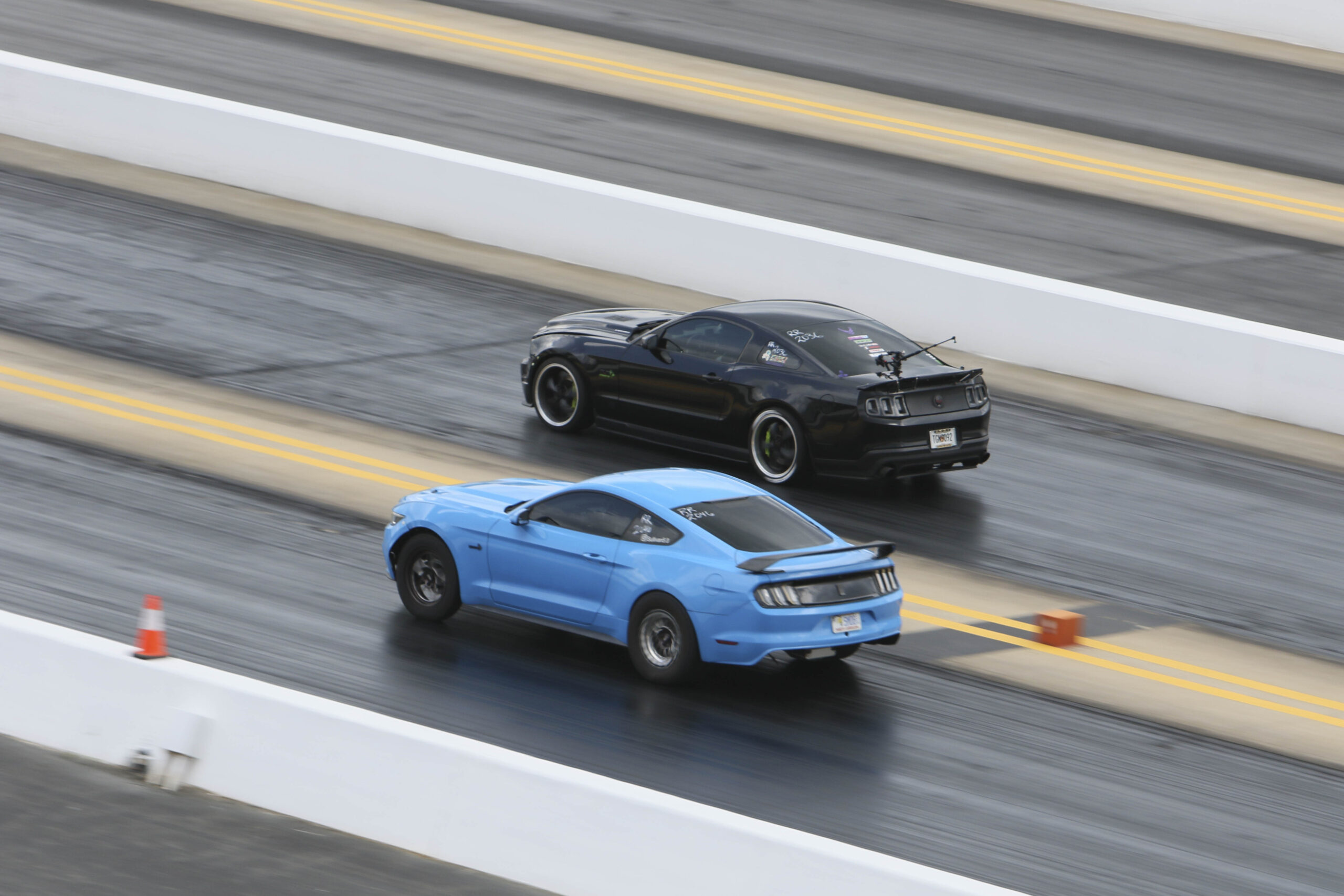 Two Ford Mustangs racing on a drag strip during Mustang Week.