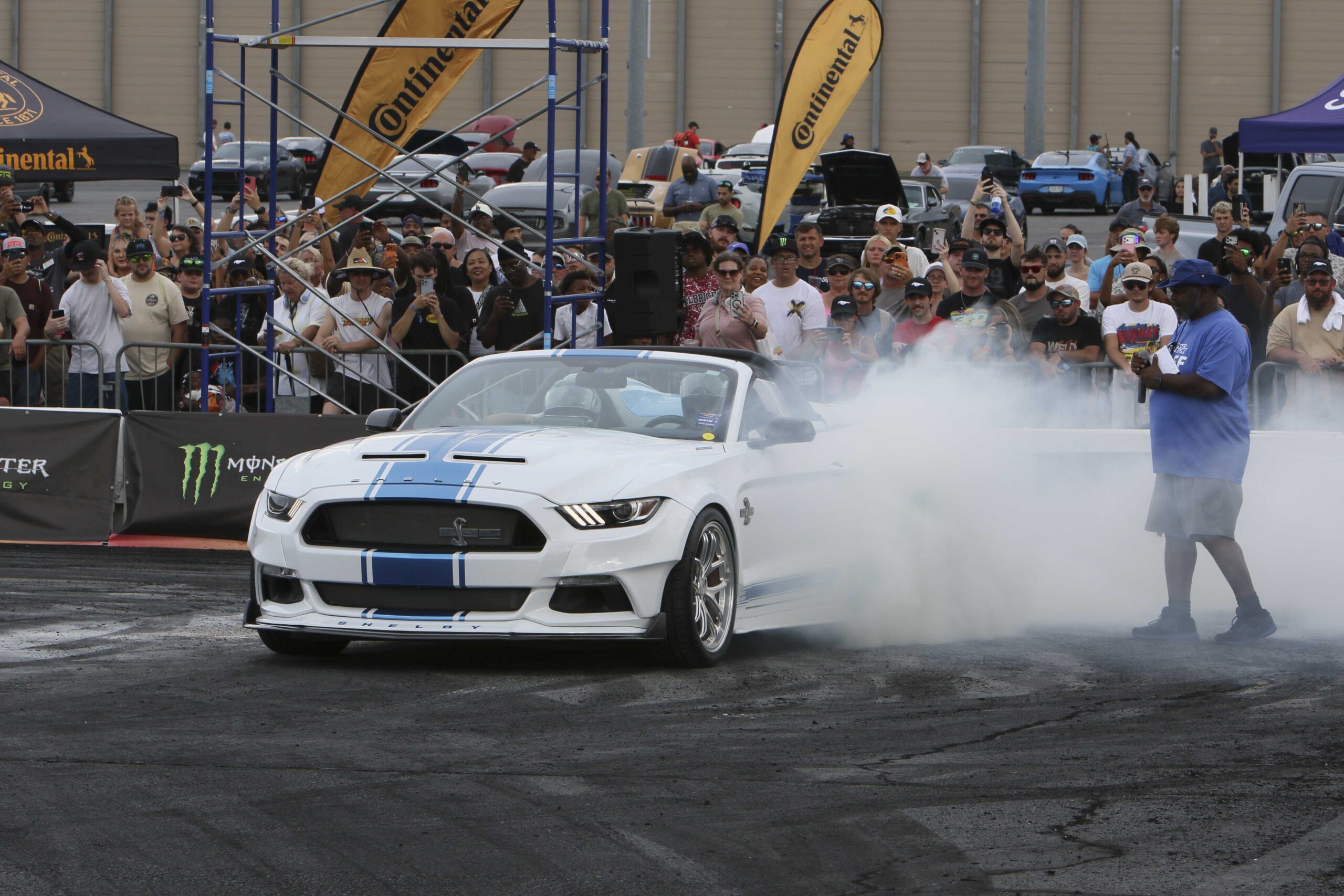 White Ford Mustang performing a burnout at Mustang Week event.