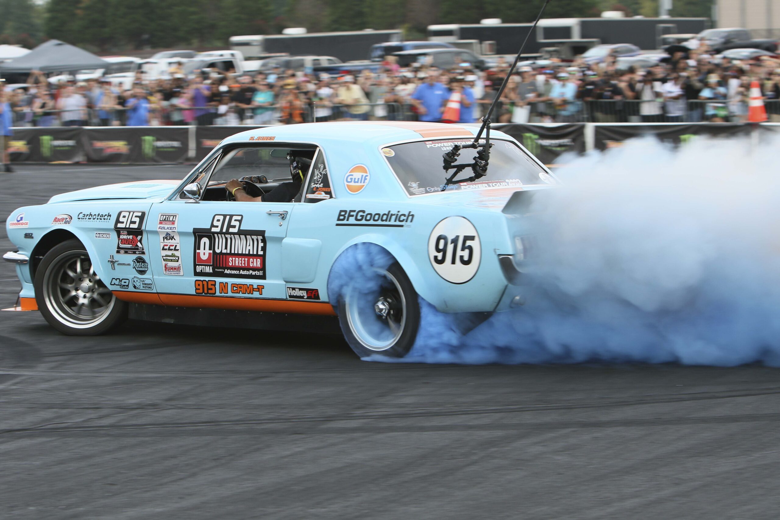 Drag racing car performing burnout at Mustang Week event.