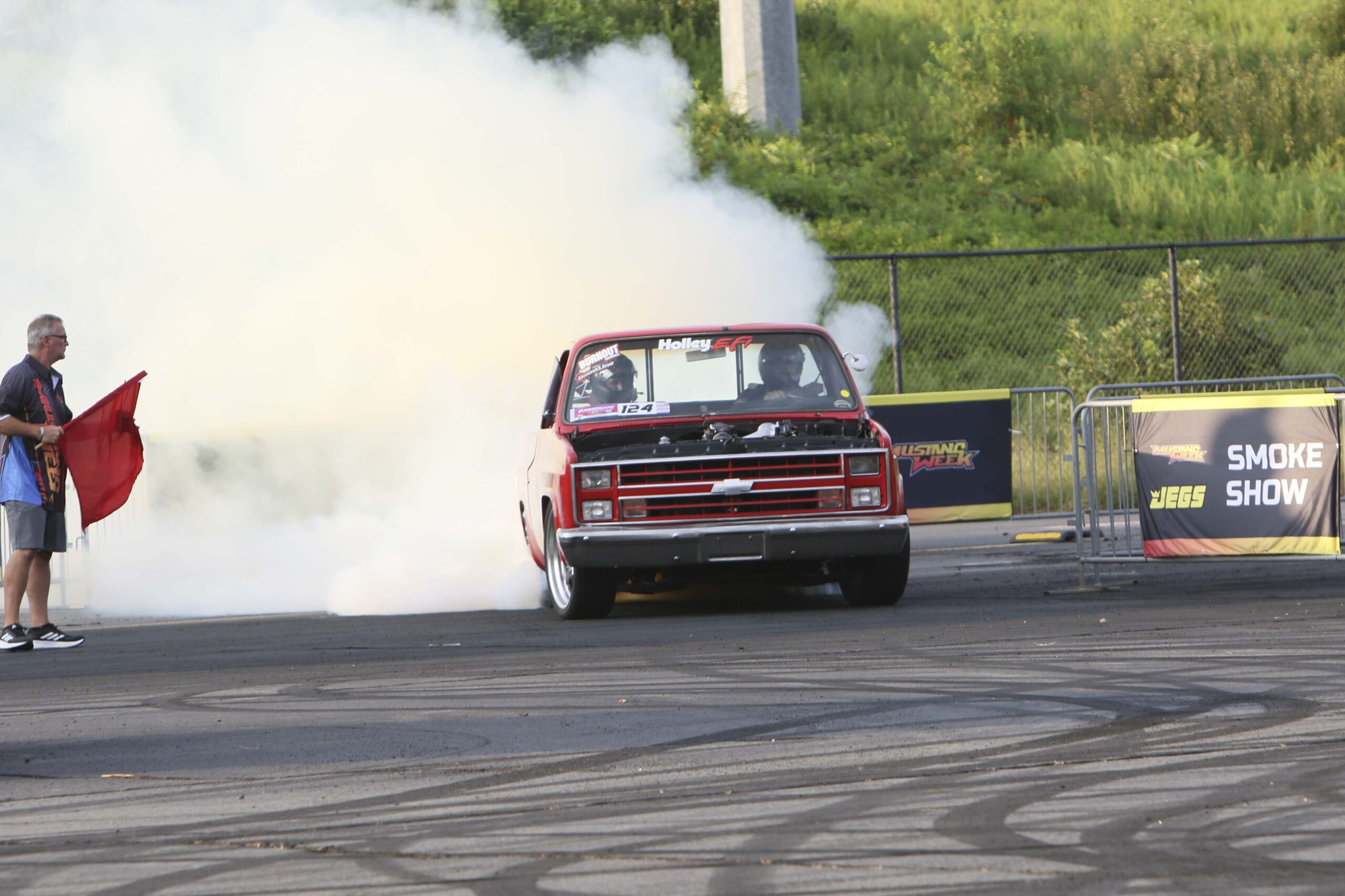 Red Ford Mustang performing a burnout at Mustang Week event.