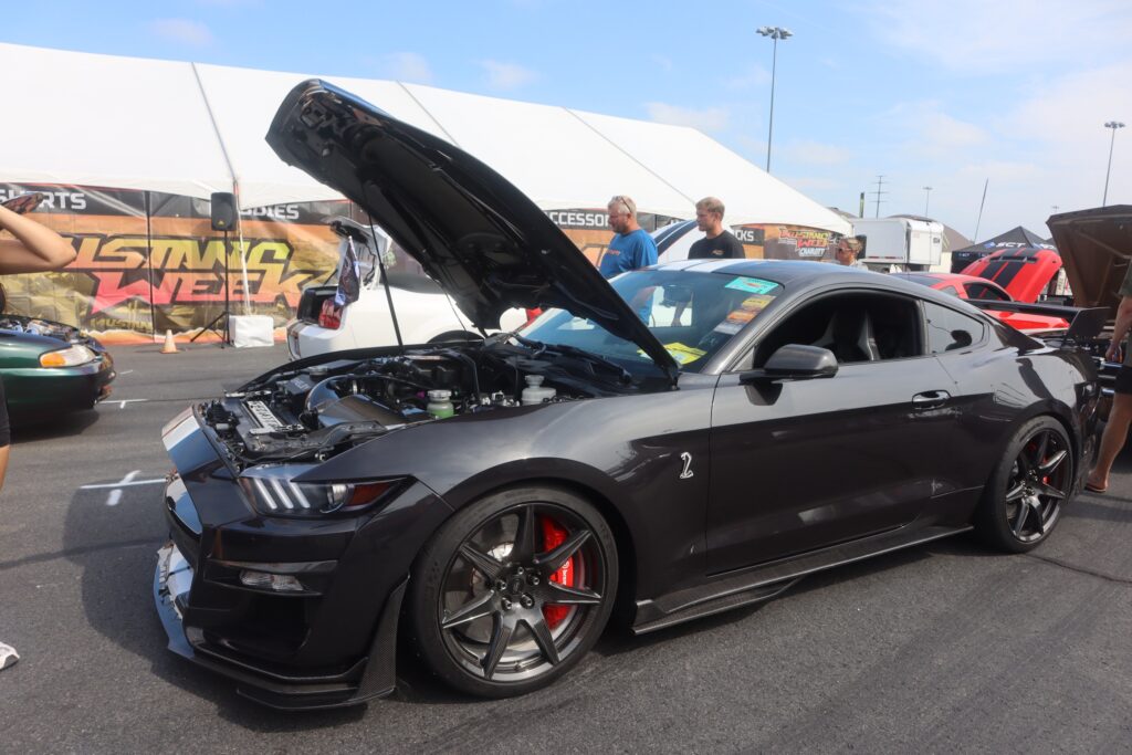 Black Ford Mustang with open hood at Mustang Week event in Charlotte.