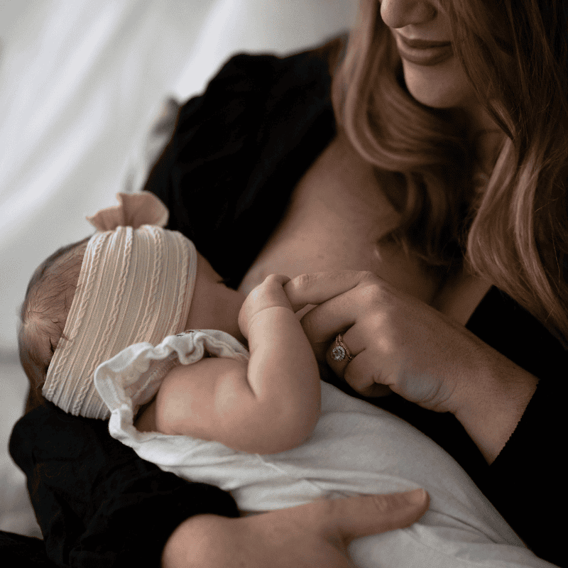 a women sitting in a chari wearing a robe looking at herself in the mirror with her right hand on her face