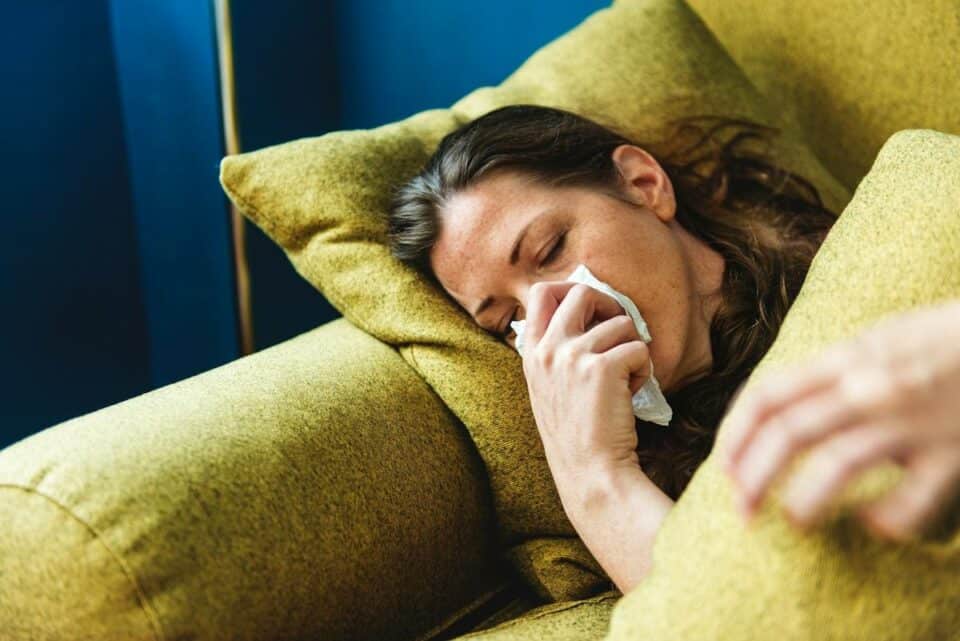 a lady on the couch blowing her nose