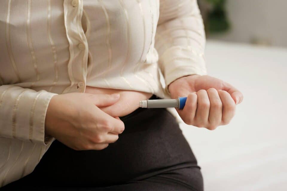 A lady injecting her stomach with a weight loss injection pen