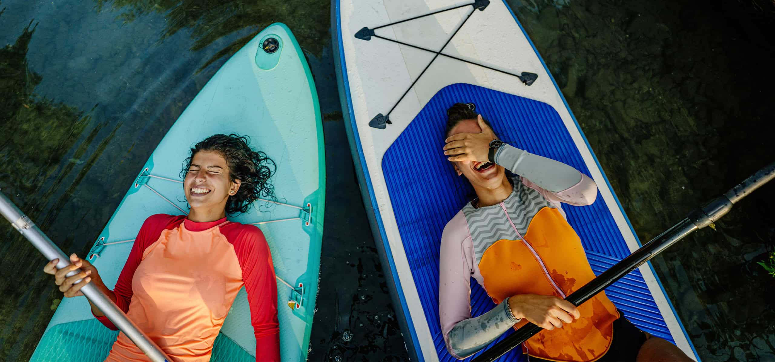 Two friends kayaking on a calm river, enjoying outdoor adventure.