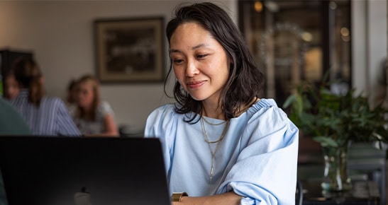 Woman working on a laptop in a cozy cafe setting.
