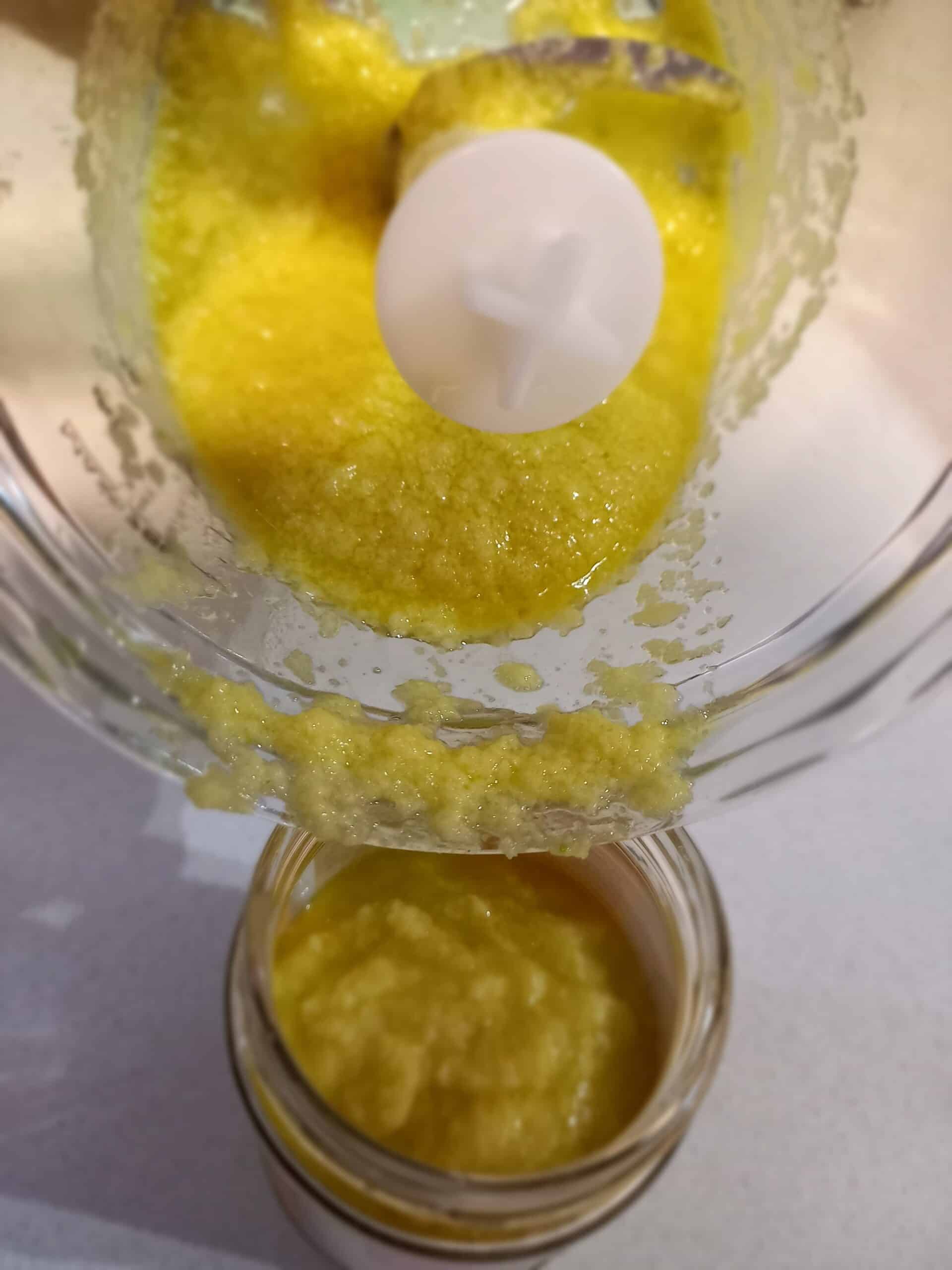 puree of garlic in a blender pouring in to a glass jar