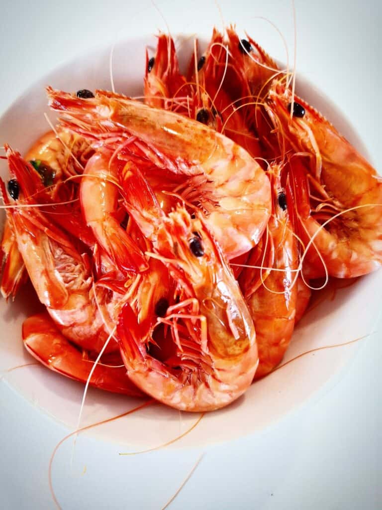 Whole cooked king prawns in a white bowl plate