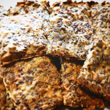 11 Square pieces of Sunflower seed crisp bread piled up on a plate
