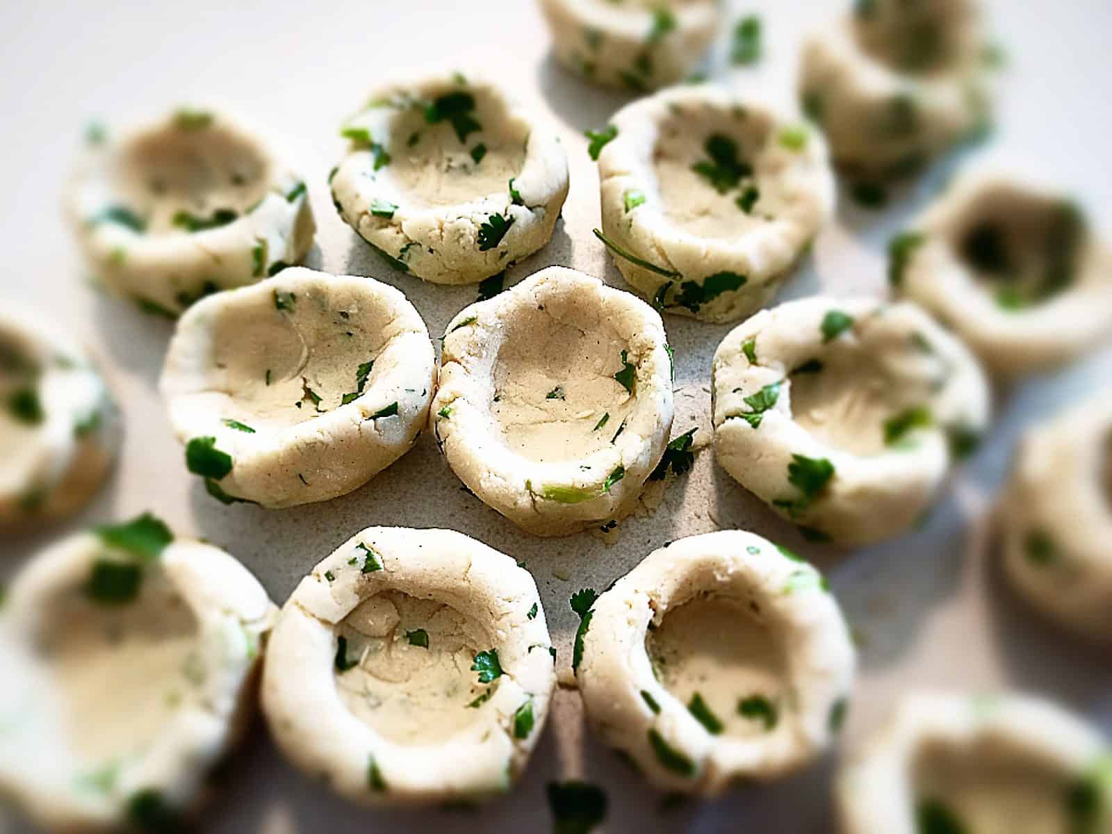 Uncooked masa corn and coriander dumplings on a creamed colored bench top
