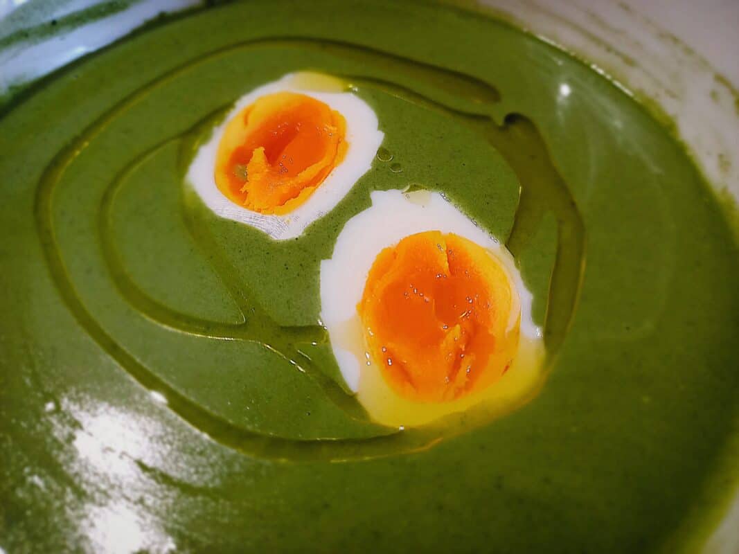 Nettles soup with egg halves on top and drizzle of olive oil
