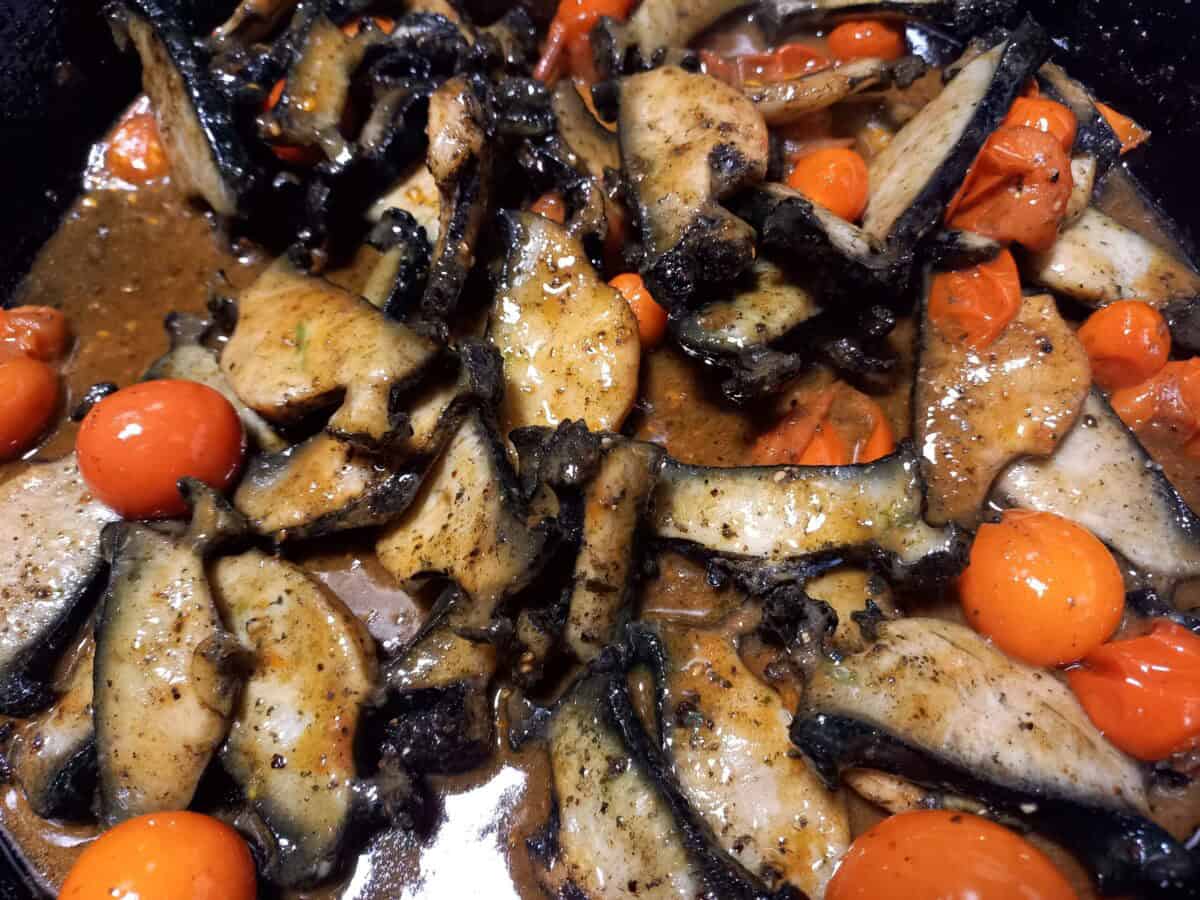 A close up picture of sauteed Paua and whole cherry tomatoes