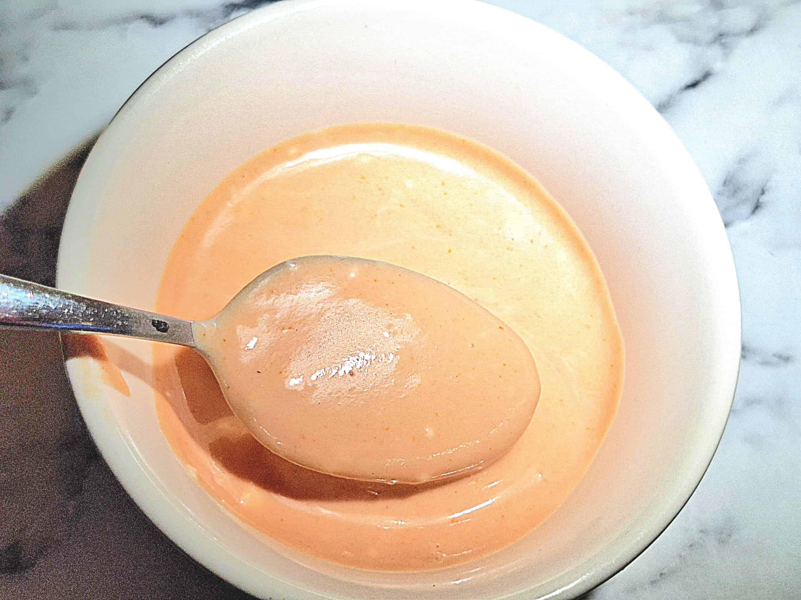 seafood cocktail sauce in a round ramekin with a spoon in it holding up some sauce