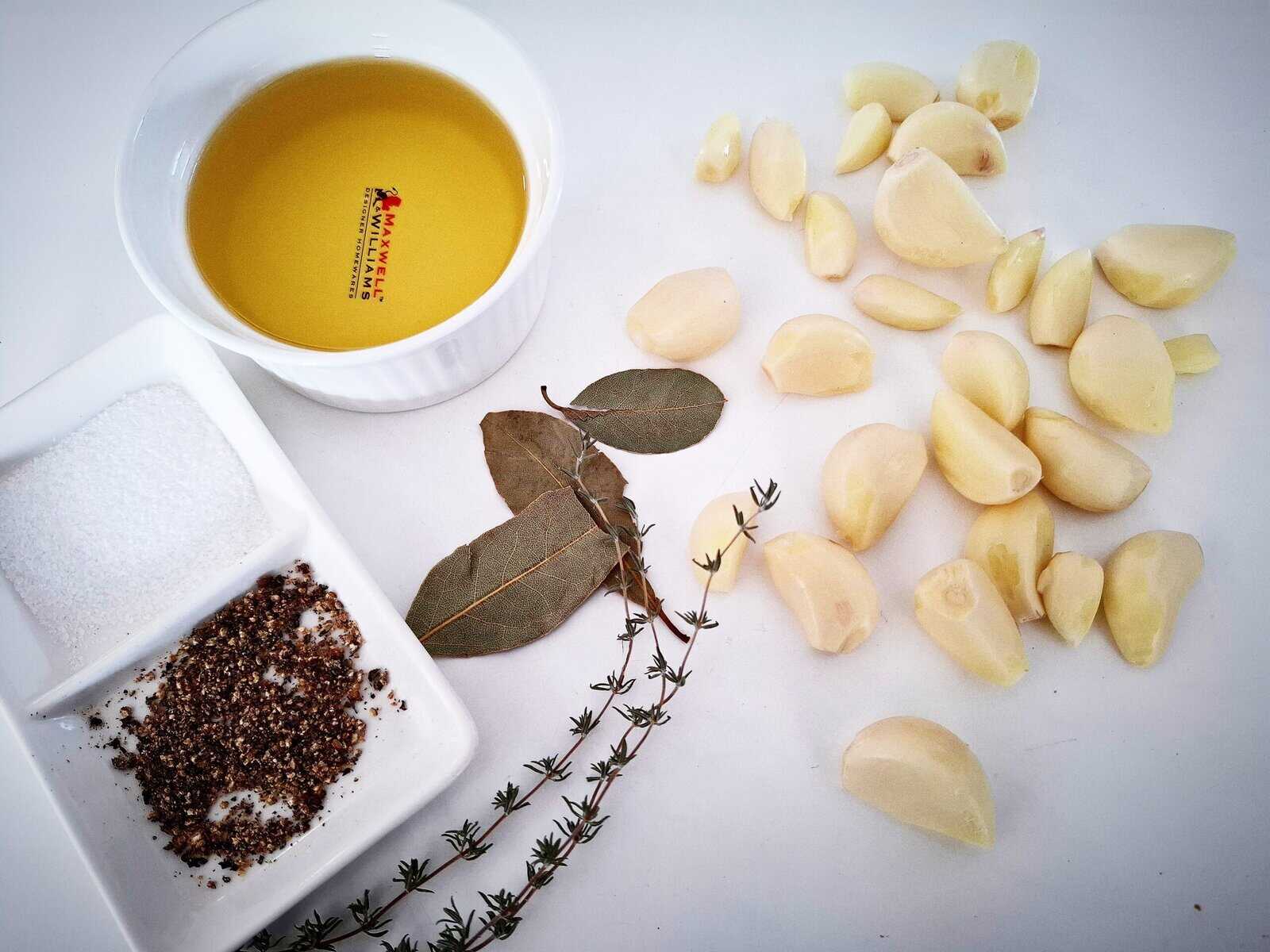Ingredients needed to make garlic confit on a white tabletop