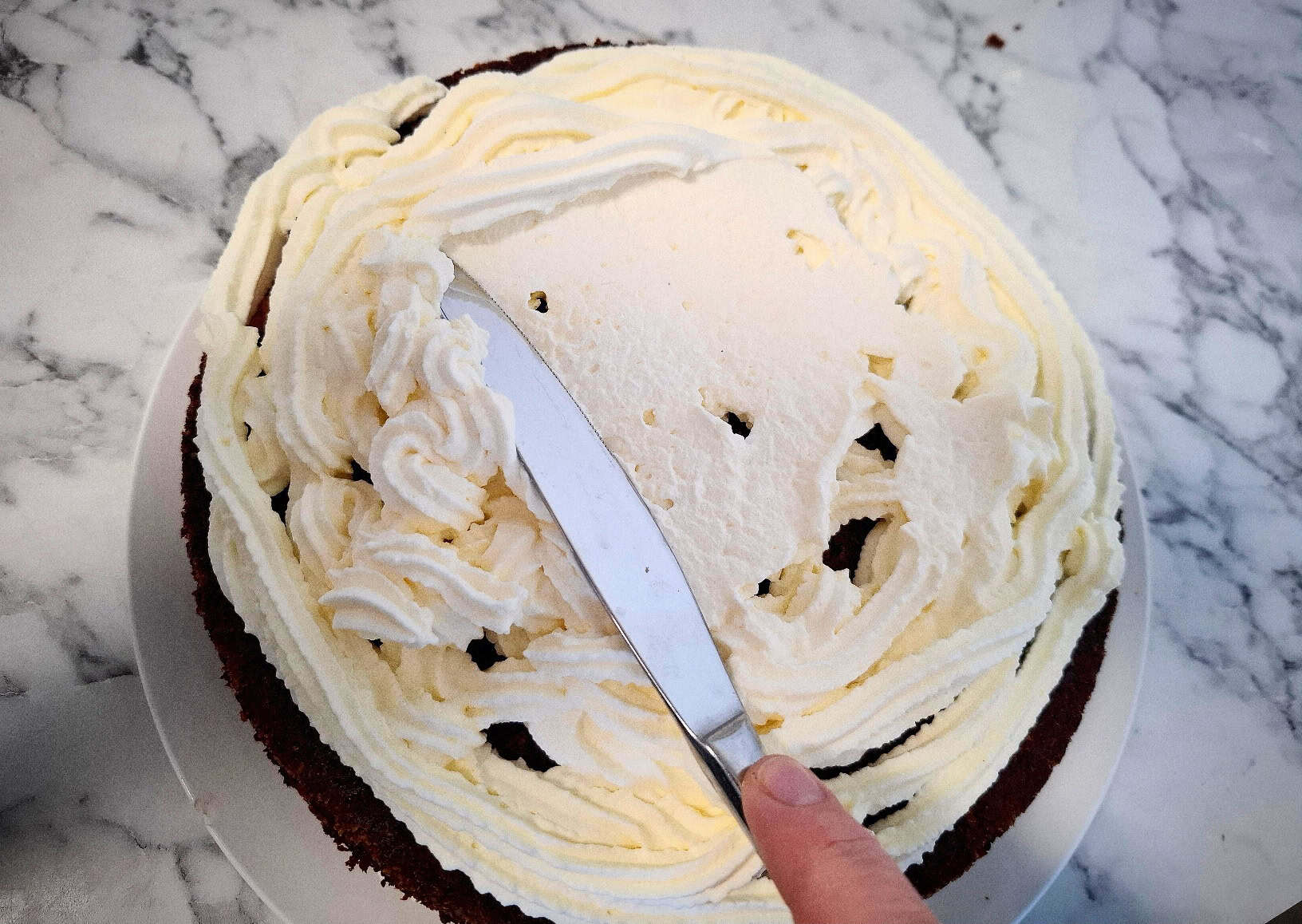 Spreading a layer of cream on top of the banana slices.