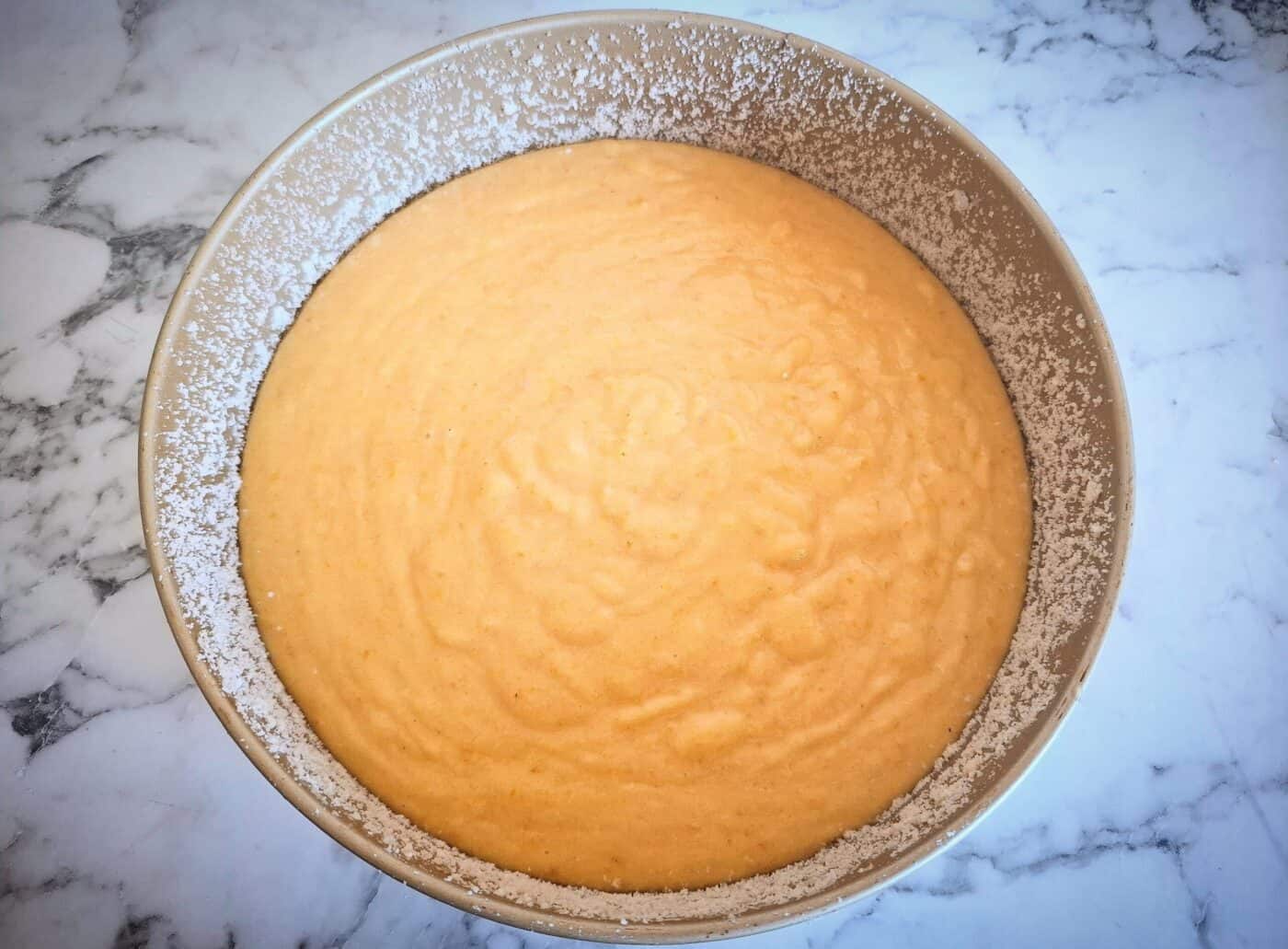 Orange and almond cake batter in a greased and almond meal covered cake tin ready to go in the oven.