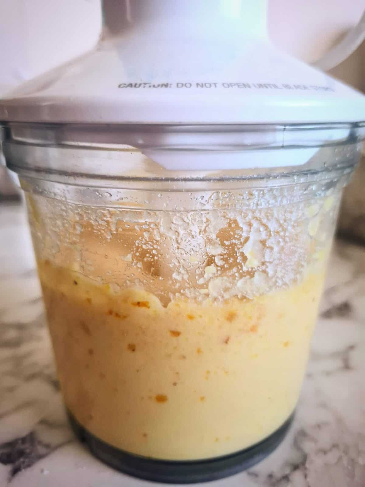 All the orange and almond cake ingredients being mixed in a small blender with clear base and white top.