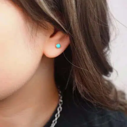 Model wearing the mini turquoise studs, highlighting subtle glow and size