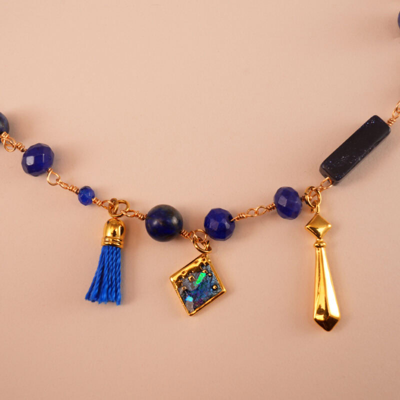 "Close-up of Lapis Lazuli charm necklace showcasing intricate gold pendants, vibrant beads, and tassel detail."