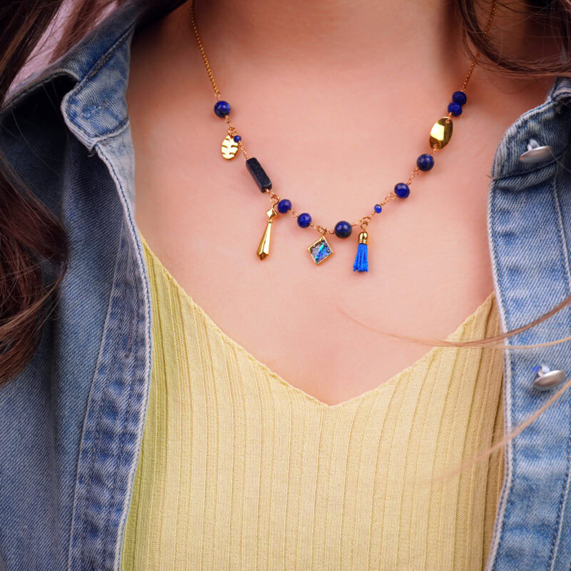 "Wearing Lapis Lazuli charm necklace, with a vibrant blue tassel and gold pendant details enhancing the outfit."