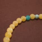 Close-up of amber and aquamarine beads with floral charm and silver accents