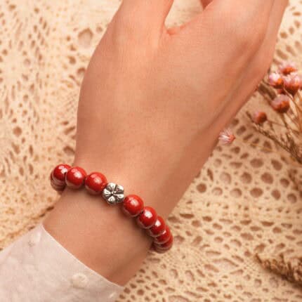 Wrist view of red cinnabar flower bracelet styled for a festive look