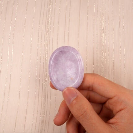 Hand gently holding the Kunzite & Mica worry stone to show its soft pastel tone and size