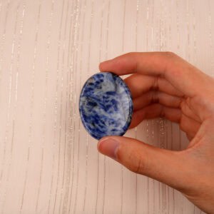 Fingers holding the Blue Apatite worry stone, showing size and smooth surface