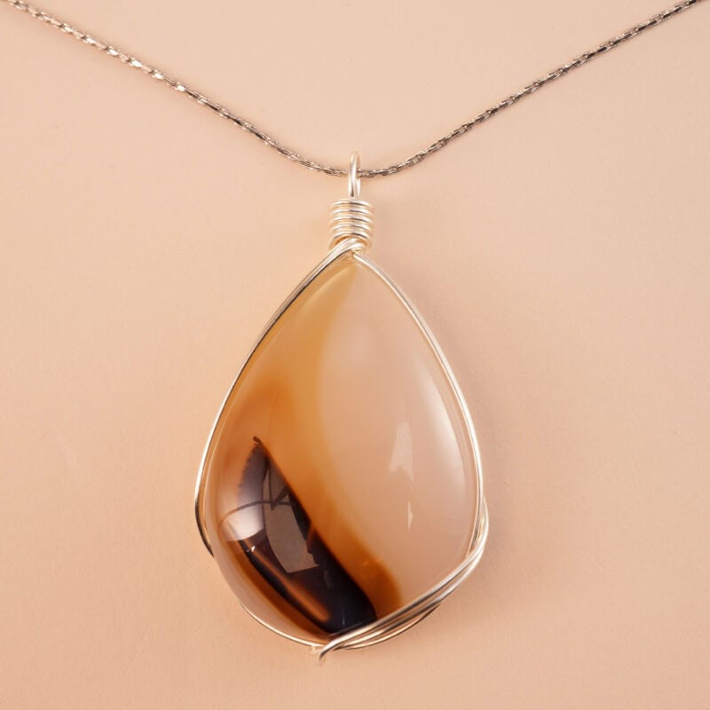 Handcrafted agate teardrop pendant necklace on a neutral or nature-inspired background