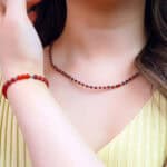 Model wearing blue apatite and red agate clavicle necklace with neutral top