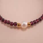 Close-up of garnet and pearl beads strung on elastic cord