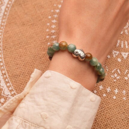 Wrist wearing the agate bracelet, showing the contrast between pink and green tones, elegant and spiritual.