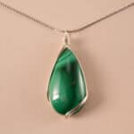 Handmade malachite teardrop pendant necklace on a neutral background