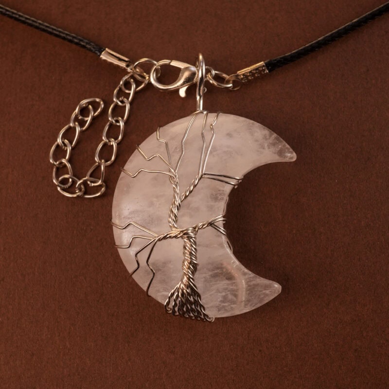 Close-up of woven clear quartz stone in crescent moon pendant setting